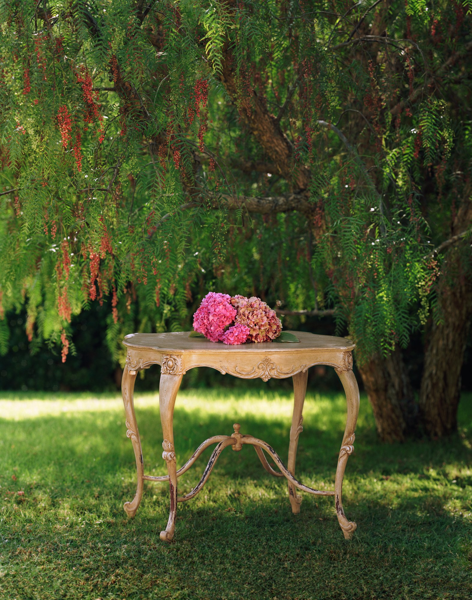 Hélène, a serpentine Napoleon III style side table in a pale limed finish with carved cabriole legs and stretchers, hydrangeas on top