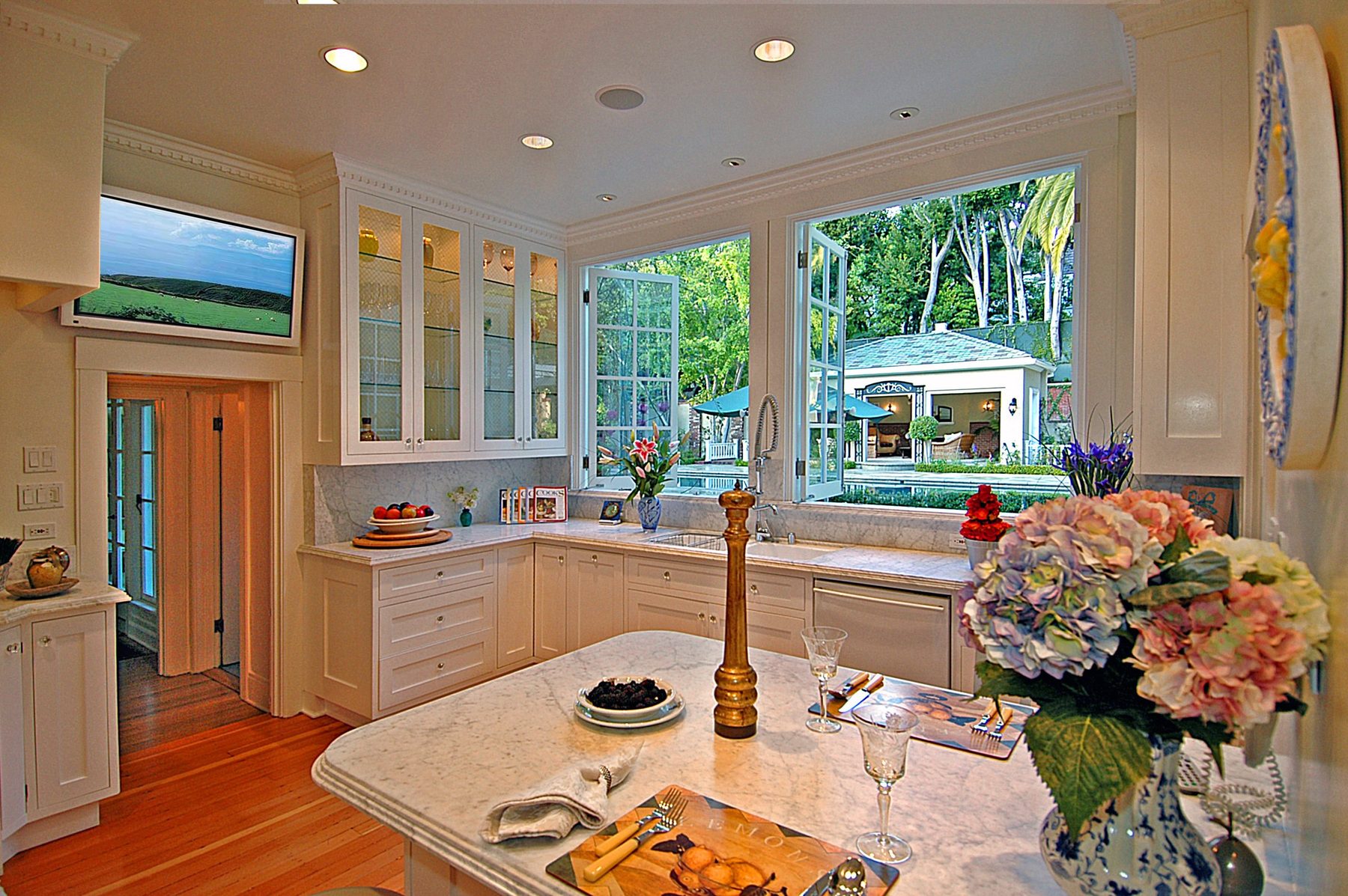 Kitchen with a marble island and a window looking out to the pool house
