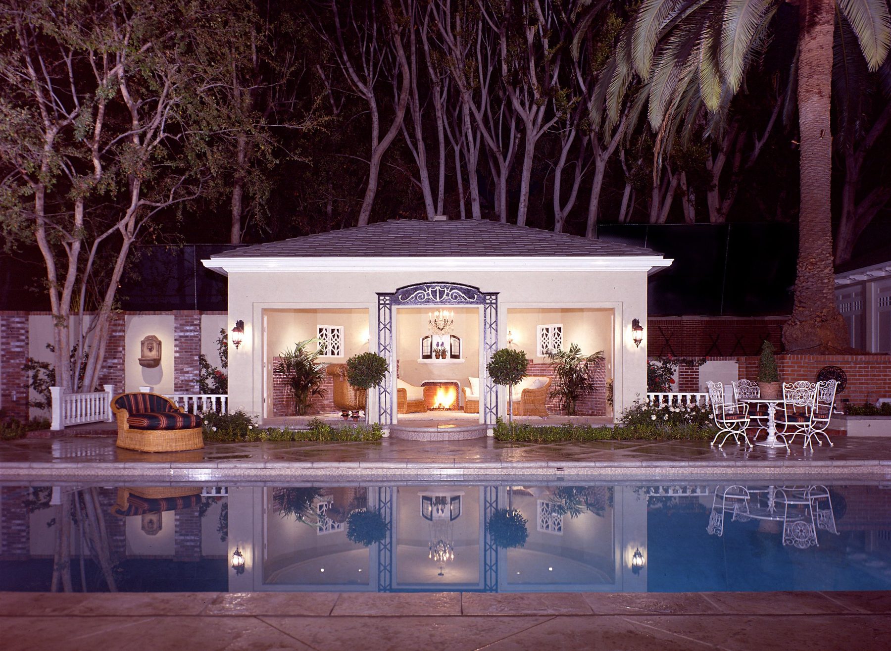 The pool house at night, lit and reflected in the pool