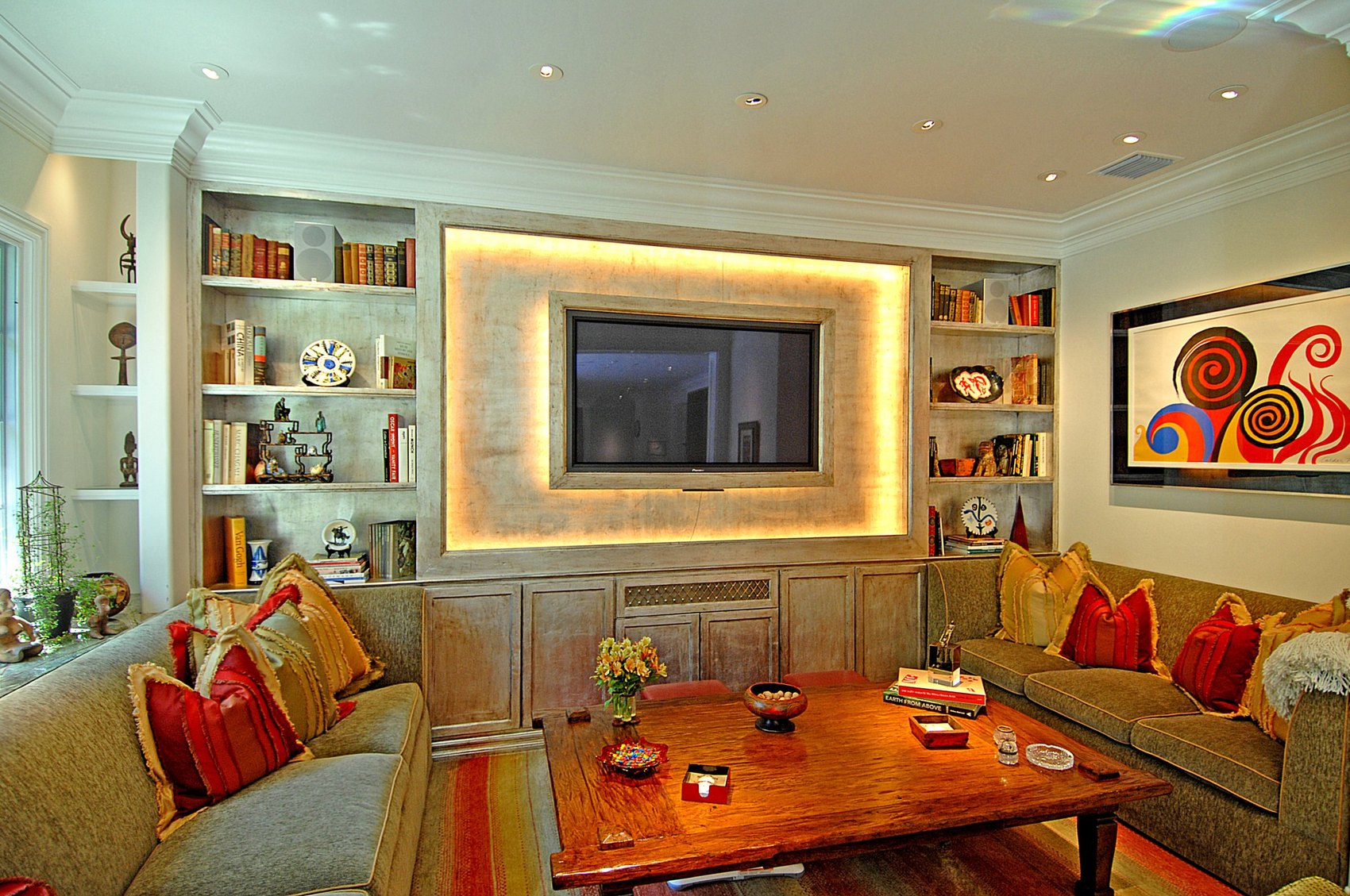 Den with a backlit limewashed surround, built-in bookcases and facing sofas