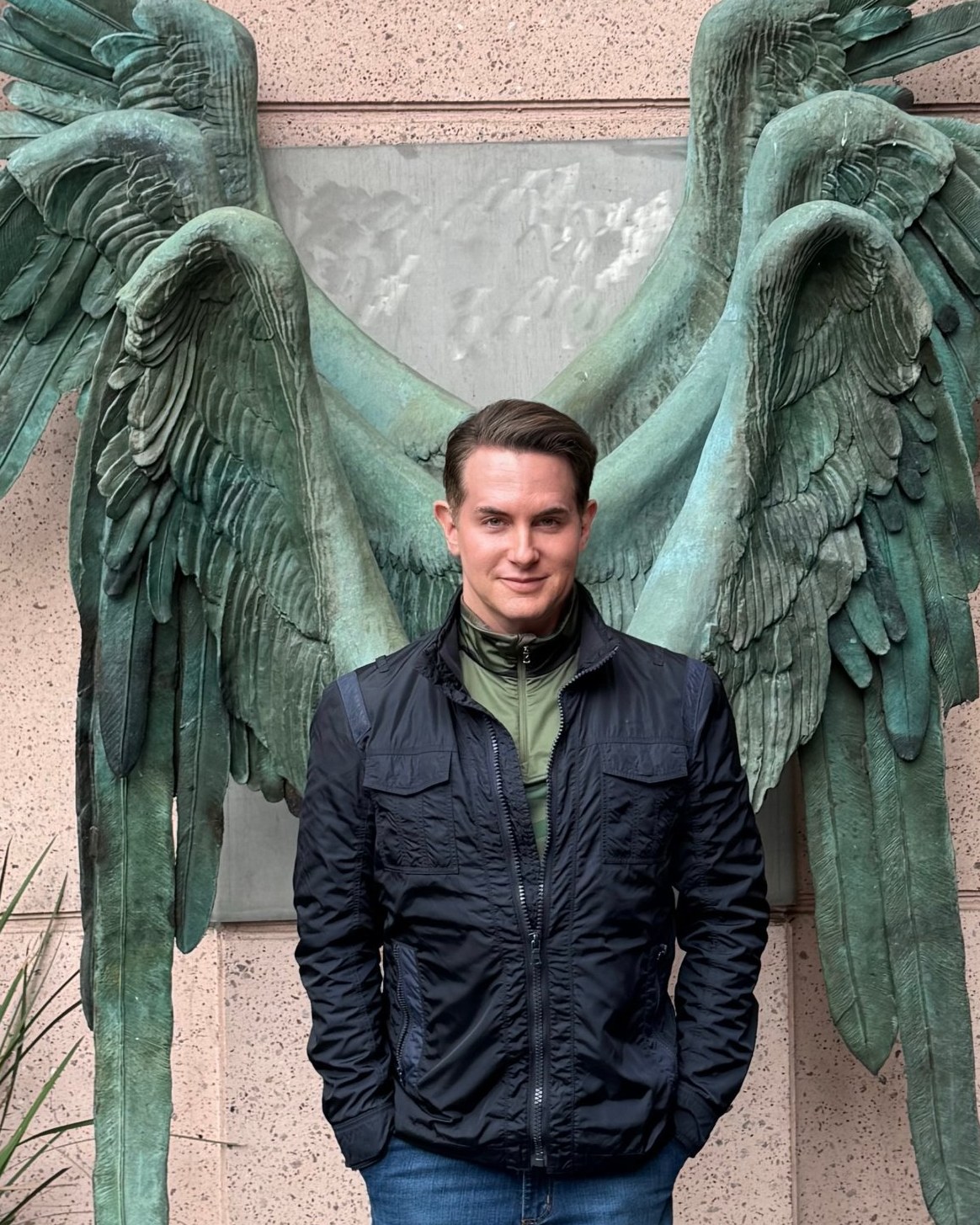Judson Rothschild standing before a pair of bronze verdigris wings