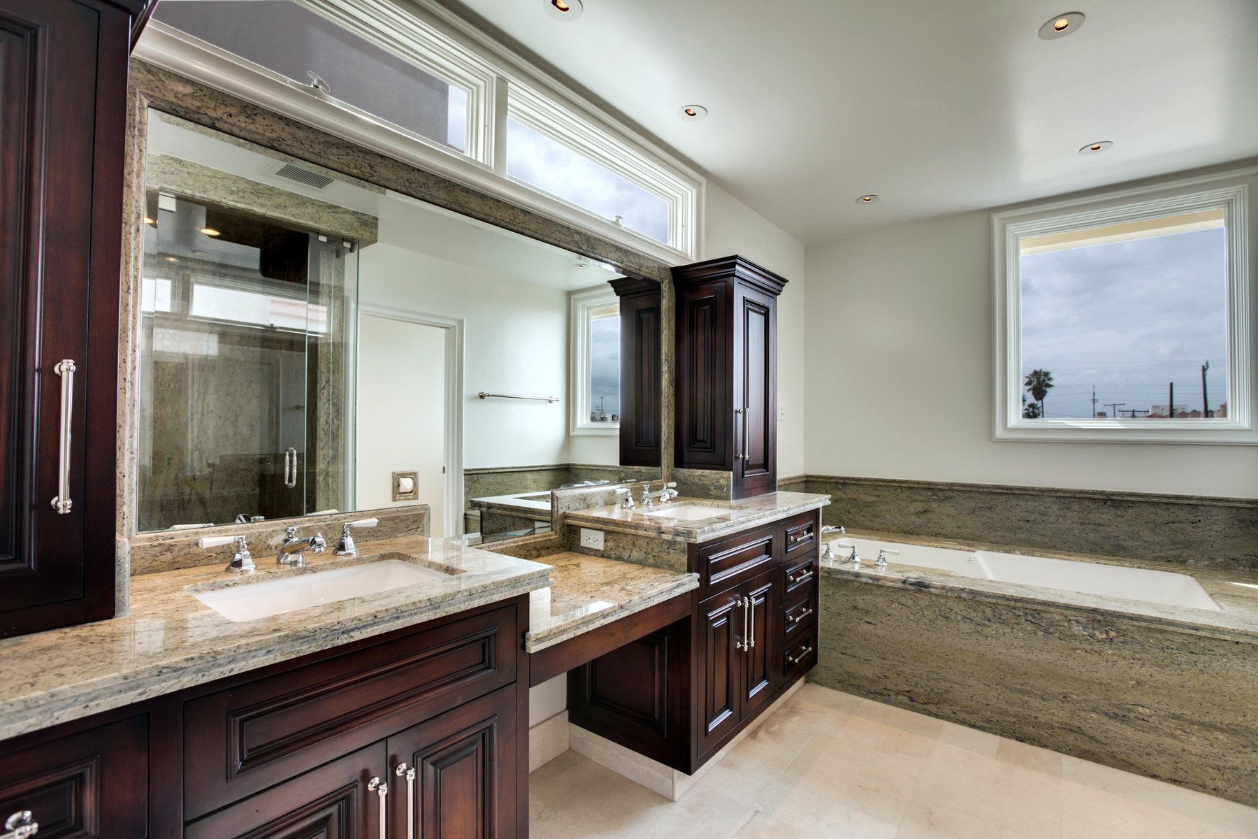 Principal bath with dark wood cabinetry, a stone counter and a tub beneath the window