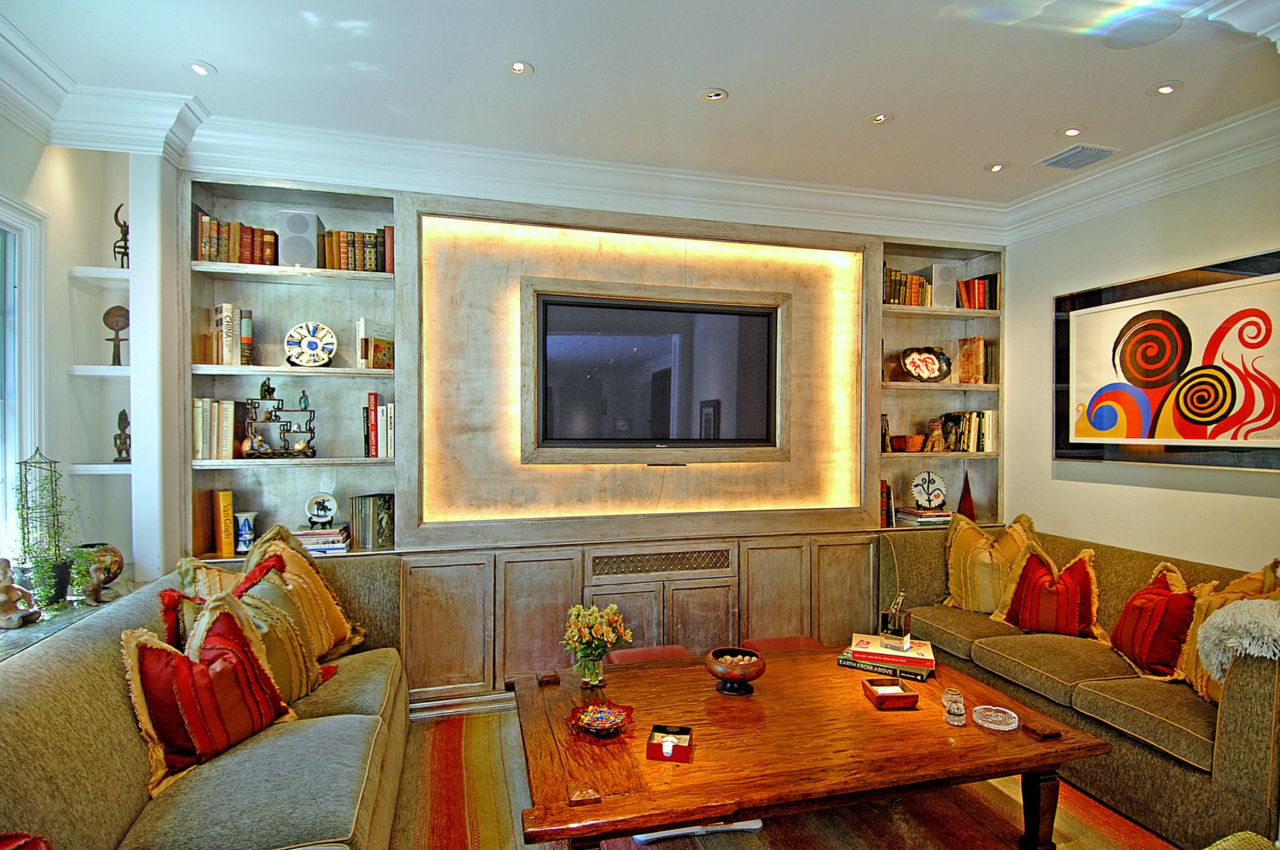Den with a backlit limewashed surround, built-in bookcases and facing sofas