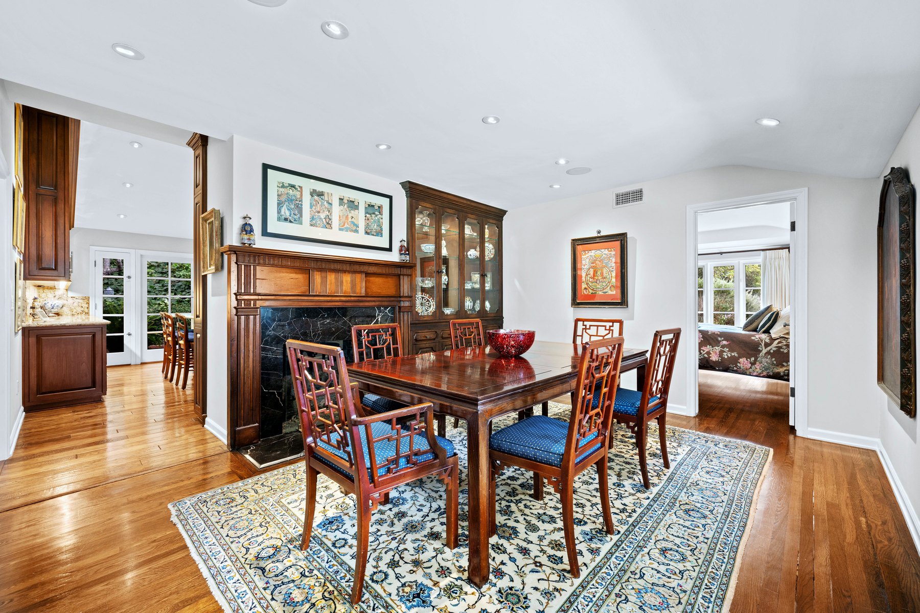 Dining room with blue upholstered chairs, a patterned rug and a glass-fronted cabinet