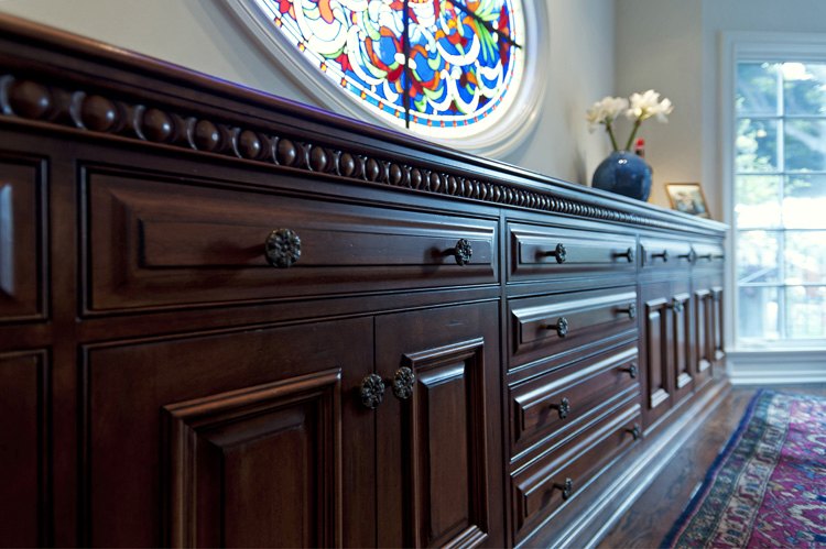 Detail of a carved wood sideboard under the stained-glass window