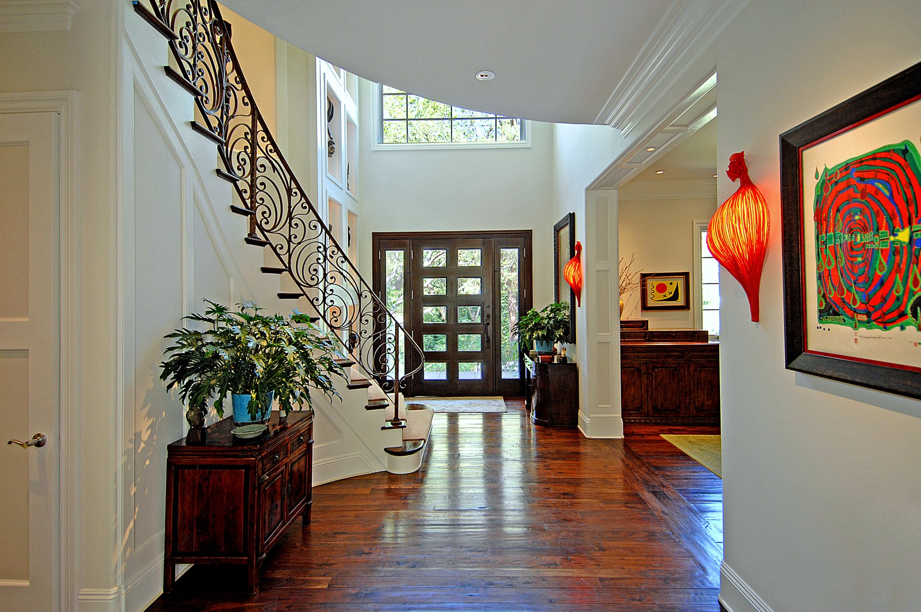 Entry hall with a curving wrought-iron stair rail and tall glazed front doors
