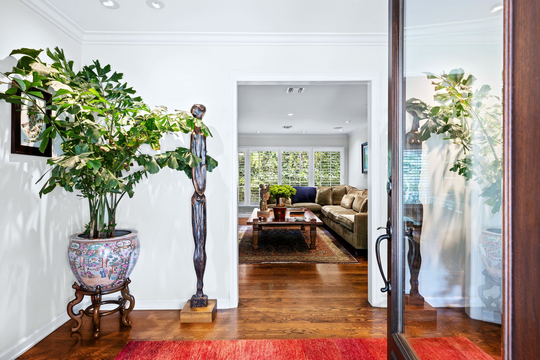 Foyer with a potted tree in a blue and white jardiniere, opening to a sitting room