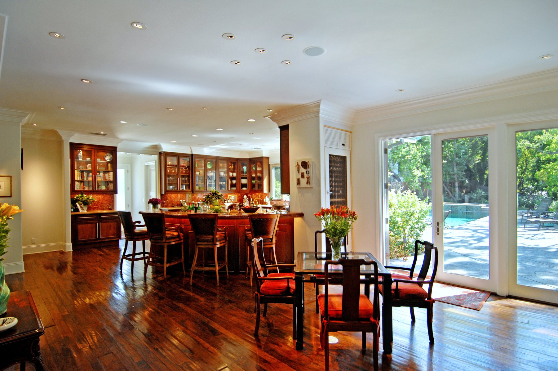 Kitchen opening to a breakfast table with red chairs and French doors to the garden