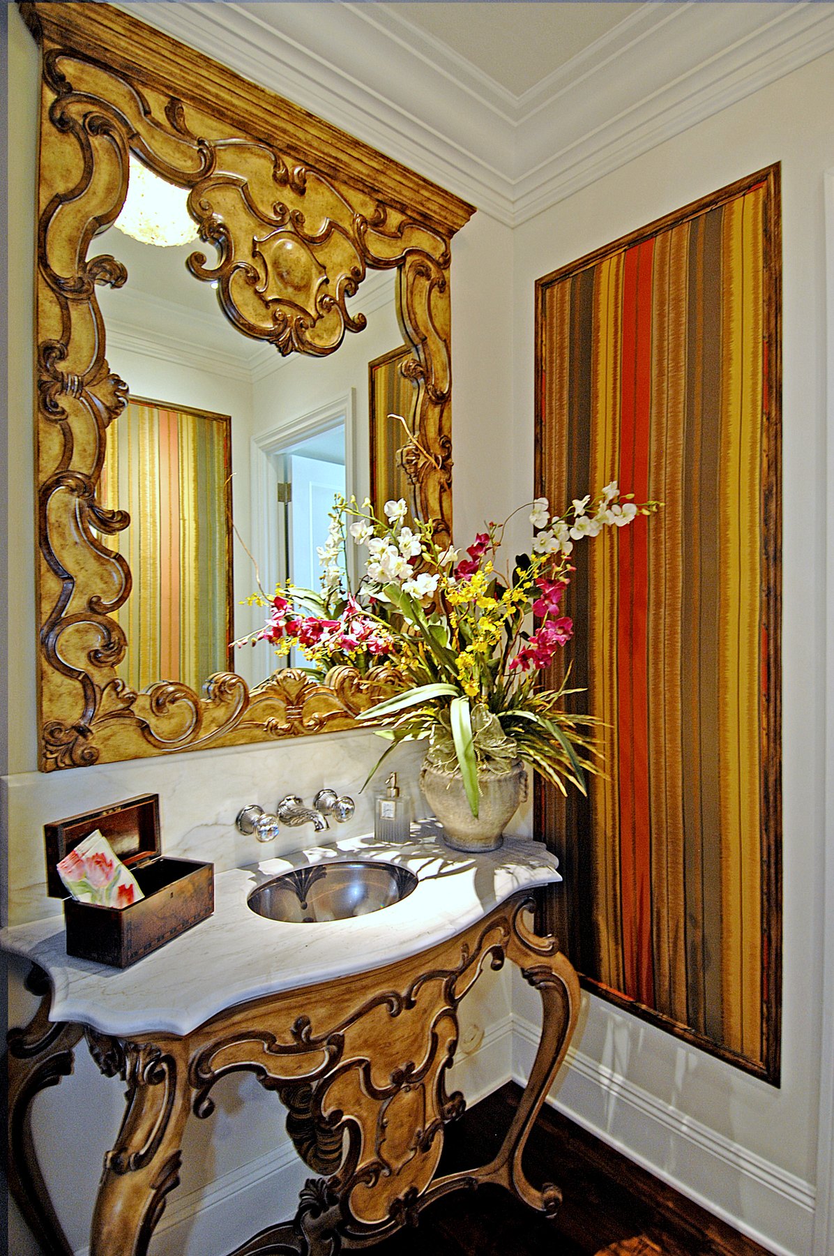 Powder room with a carved gilt mirror over a gilt console sink